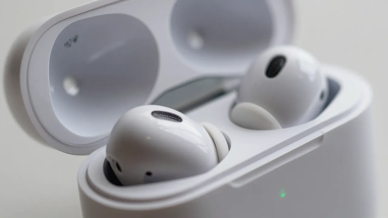 Close-up macro of wireless earbud in open charging case showing LED indicators and glossy finish